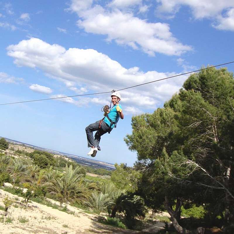 Tirandose por una tirolina en un parque de aventuras en Alicante