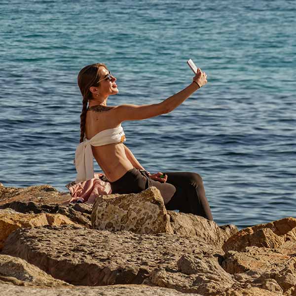 mujer elegante haciéndose foto al borde del mar